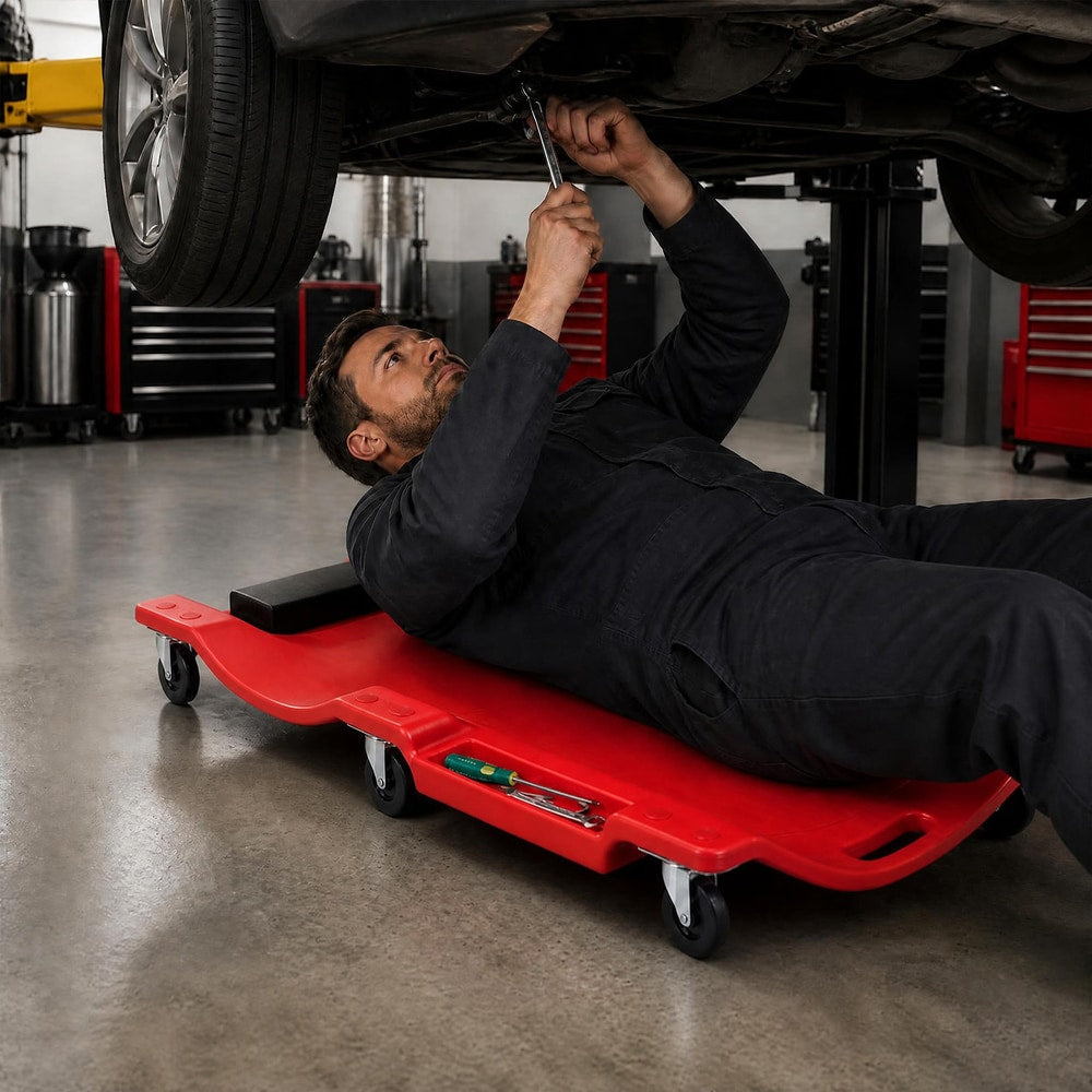 The garage creeper in use by a mechanic lying underneath a car in a workshop