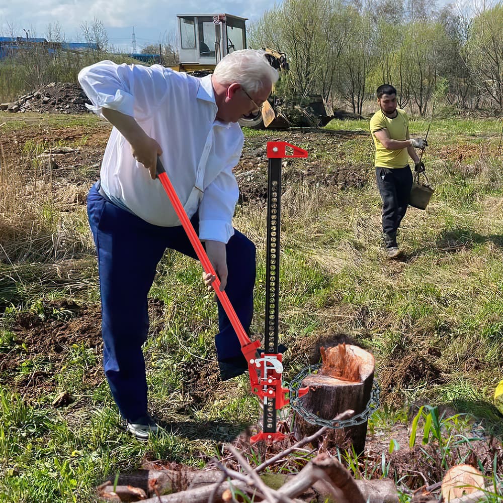 A man using the farm jack to lift a large log