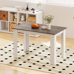 The dining table shown on a rug with a shelf unit in the background