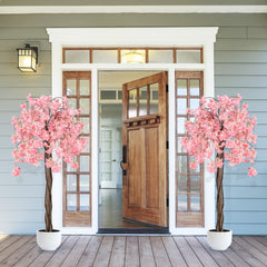 Two artificial cherry blossom trees with pink flowers flanking a wooden front door
