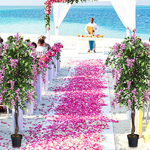 Artificial trees with pink flowers decorating a beach wedding aisle