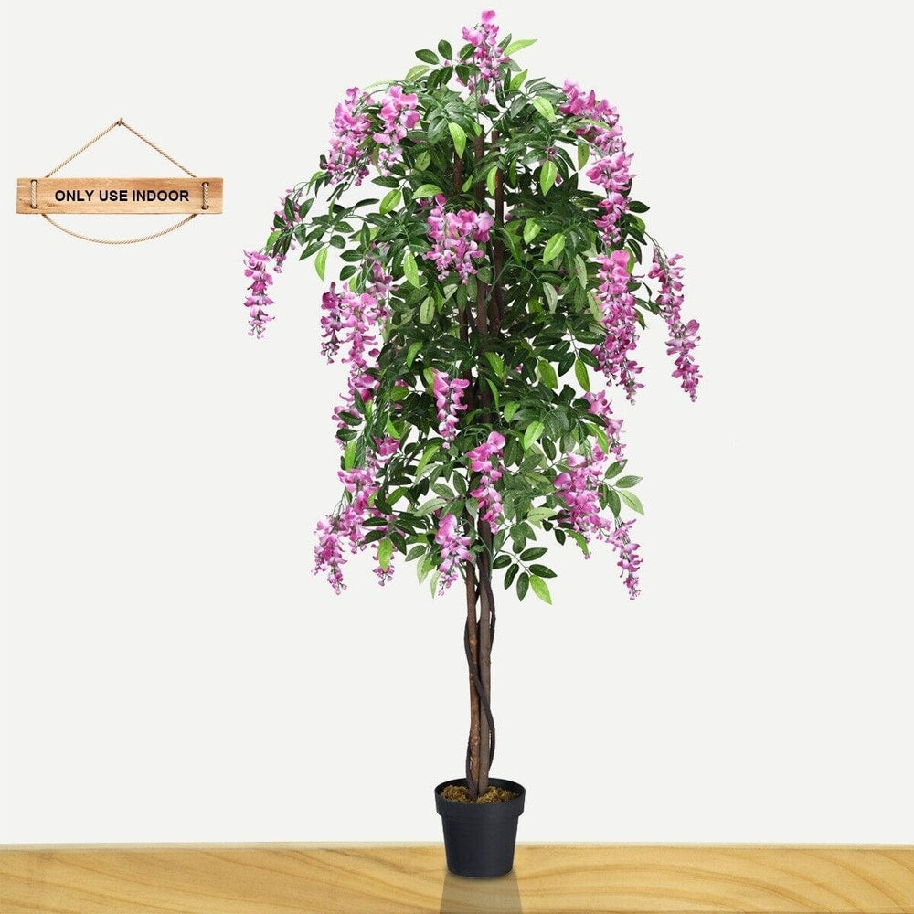 A single artificial tree with pink flowers indoors on a wooden floor