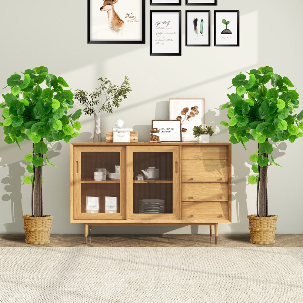 Two artificial crabapple trees in pots placed either side of a wooden cabinet