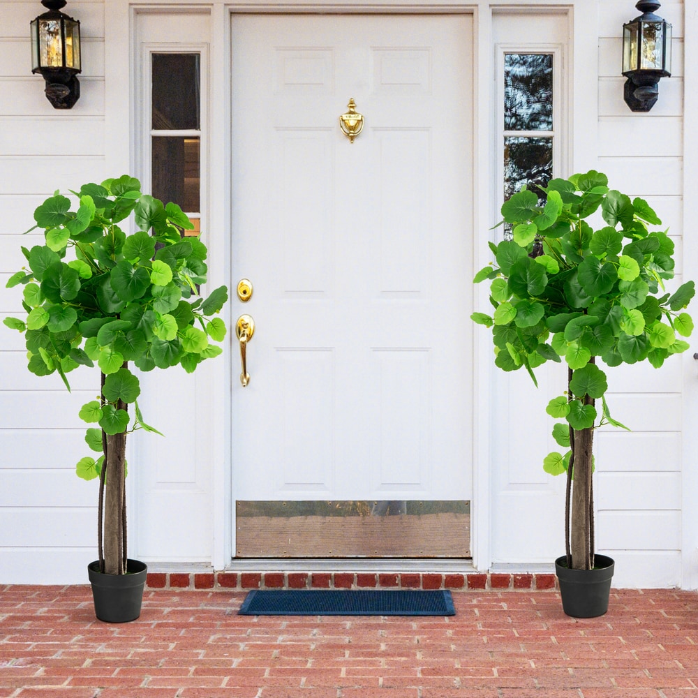 Two artificial crabapple trees in pots flanking a white front door on a brick path