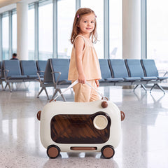 A young girl stands next to the brown kids luggage in an airport