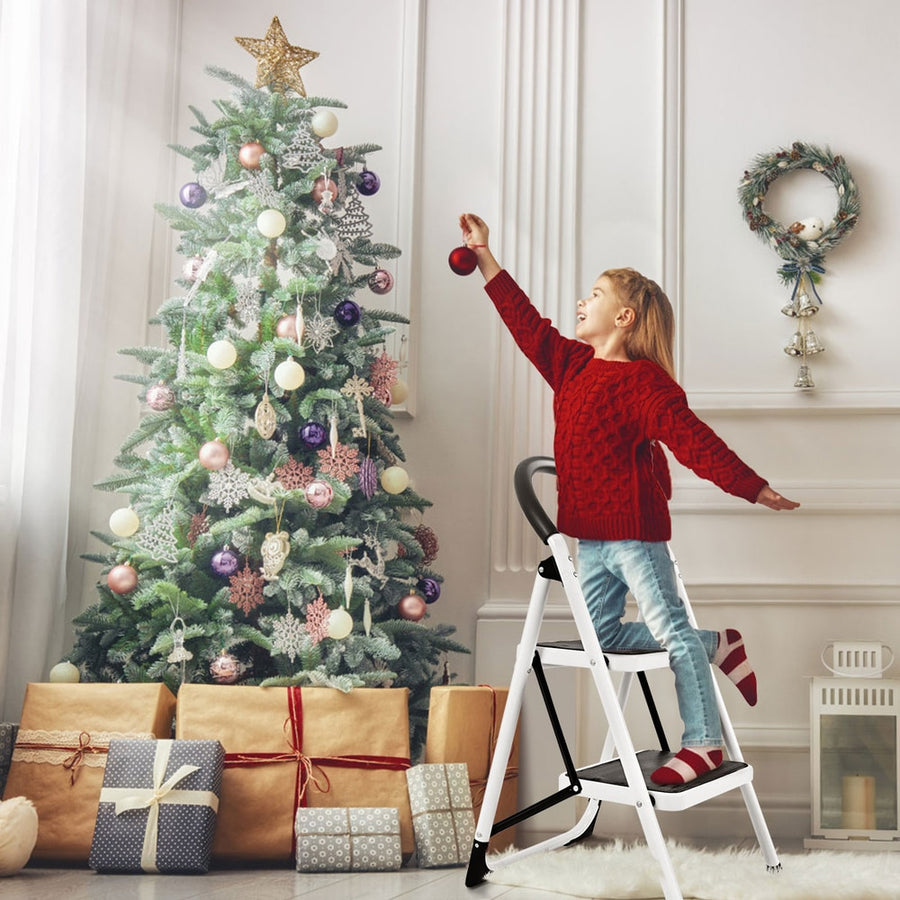 2 Step Folding Household Ladder with anti-slip platform and grip, a young girl decorates a Christmas tree