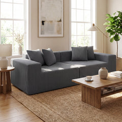 The grey loveseat positioned in a bright living room with a wooden coffee table and jute rug