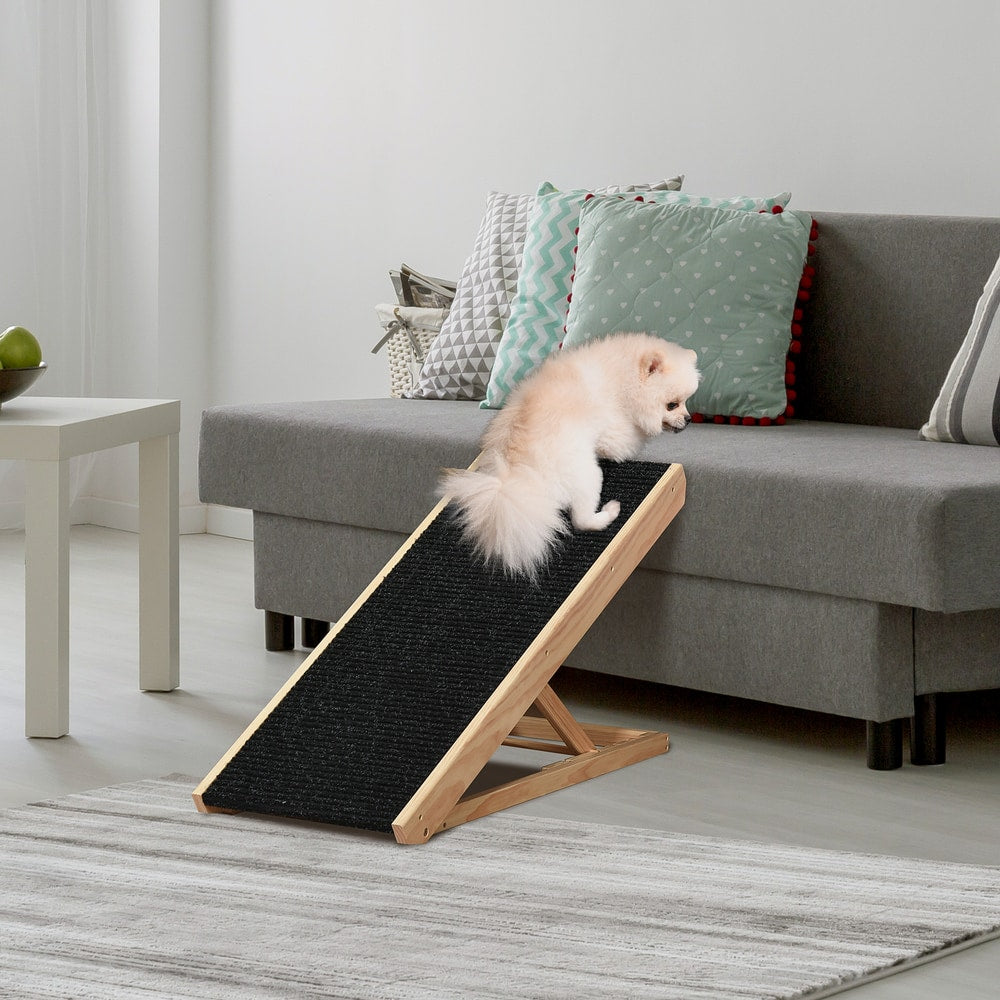The pet ramp positioned against a grey sofa with a small dog walking up to reach the seat