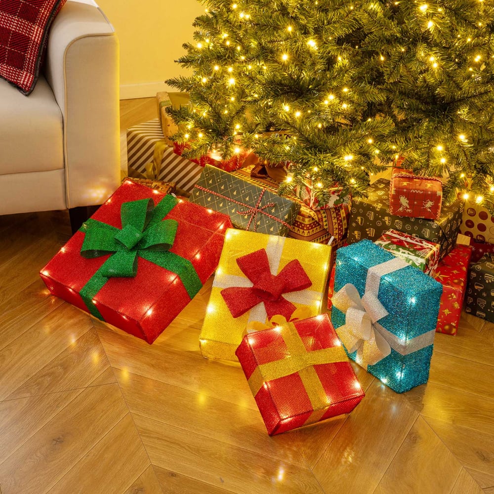 The christmas decor arranged as separate boxes on a wooden floor under a decorated tree