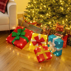 The christmas decor arranged as separate boxes on a wooden floor under a decorated tree