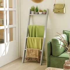 The grey blanket ladder displaying green throws in a living room