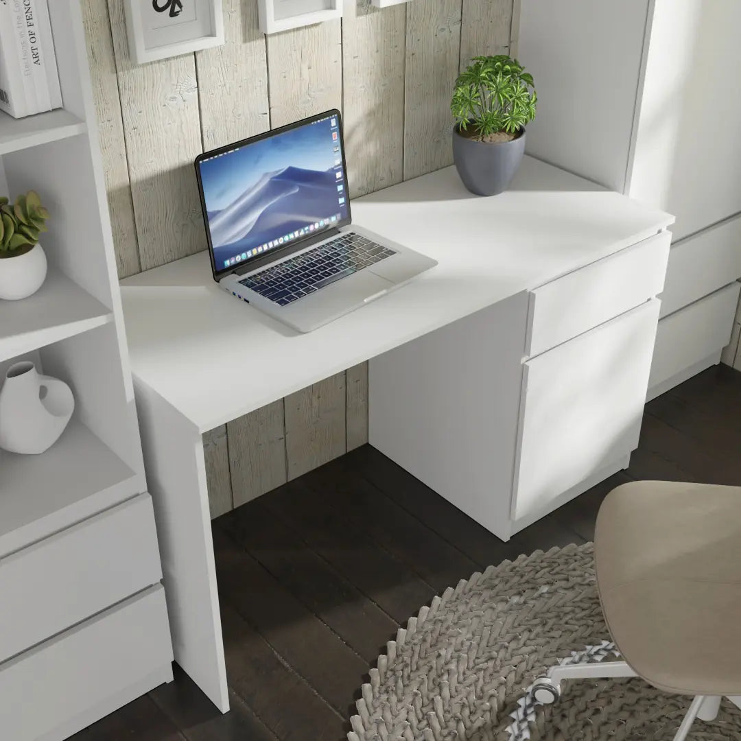 The desk in a home office setting with a laptop placed on the surface