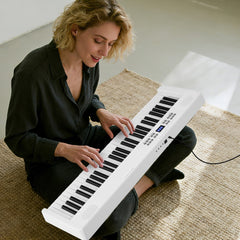 Woman playing the white electronic keyboard while sitting on the floor in a living room