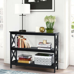 Black three-tier console table with books, a lamp and a plant, in a living room setting