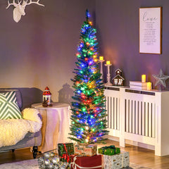 The artificial Christmas tree is lit up and decorated with presents underneath in a cosy room setting