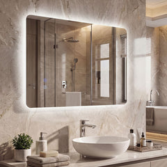 The illuminated wall mounted mirror above a bathroom sink with toiletries and a towel