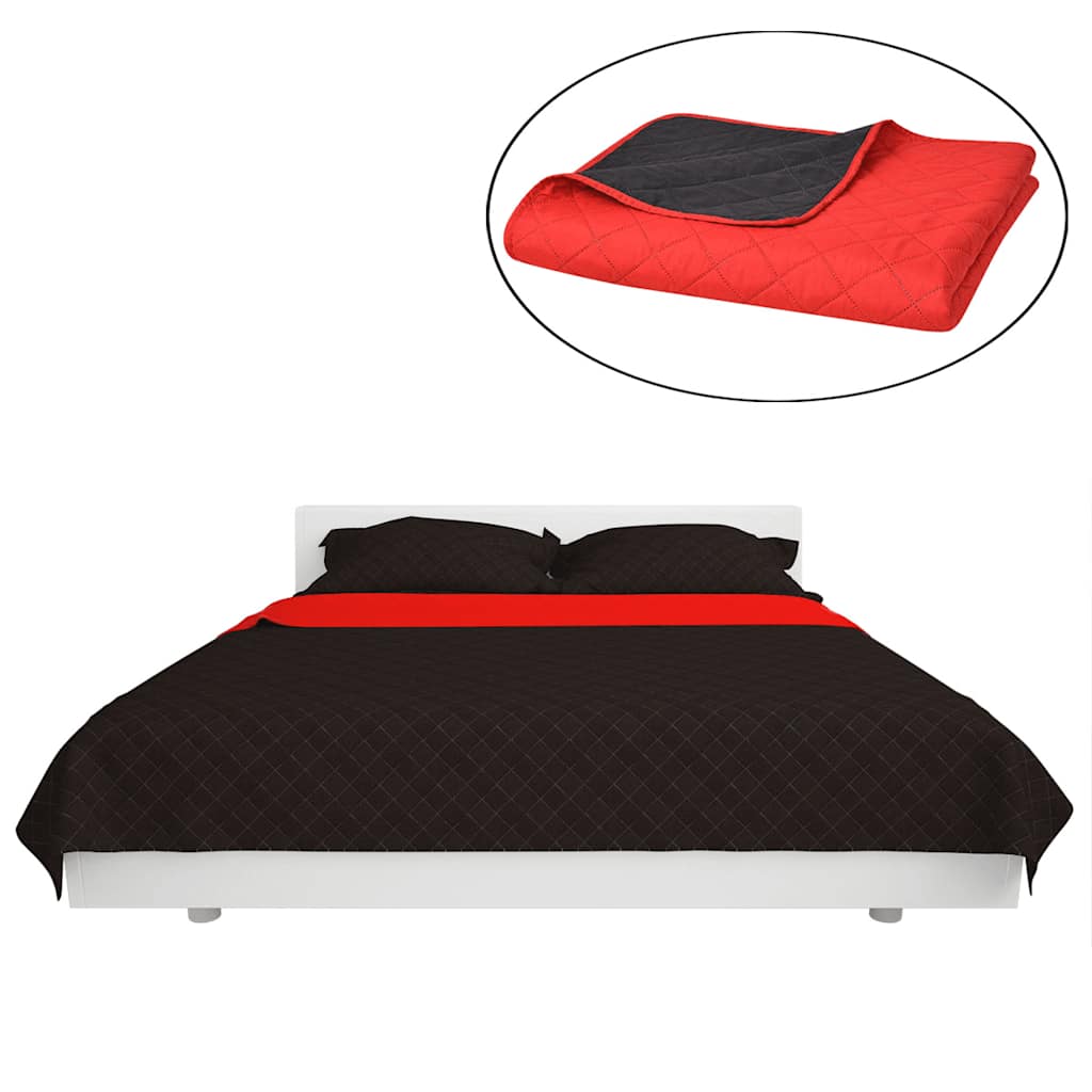 The quilted bedspread in black draped over a bed with a red accent strip