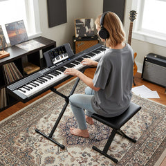 Woman playing the digital piano in a living room with records and amps