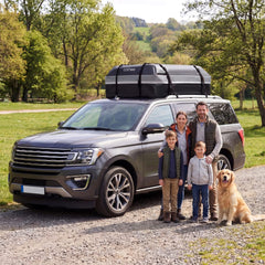 The roof bag secured to a car with a family and their dog standing beside it