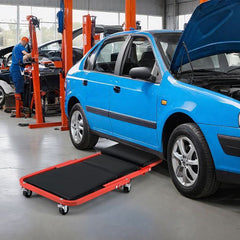 The rolling creeper seat being used under a blue car in a garage
