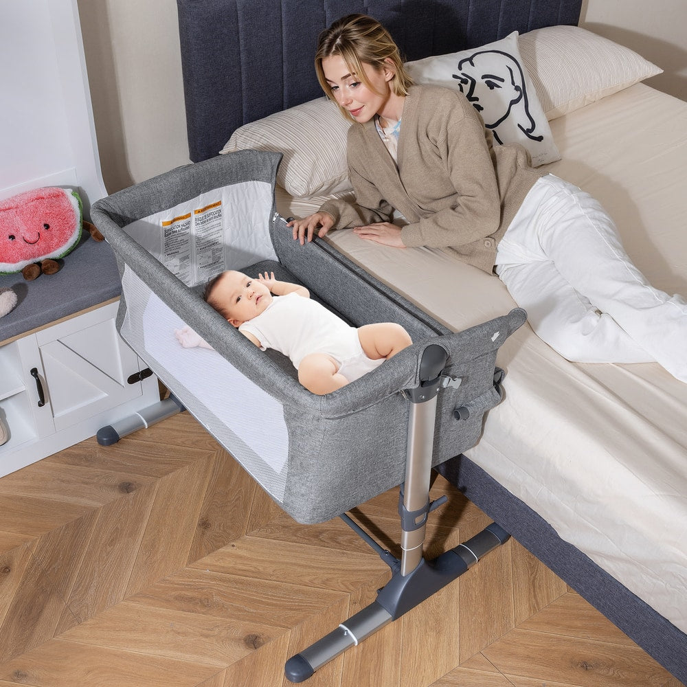The bedside sleeper in use next to a bed with a mother and baby