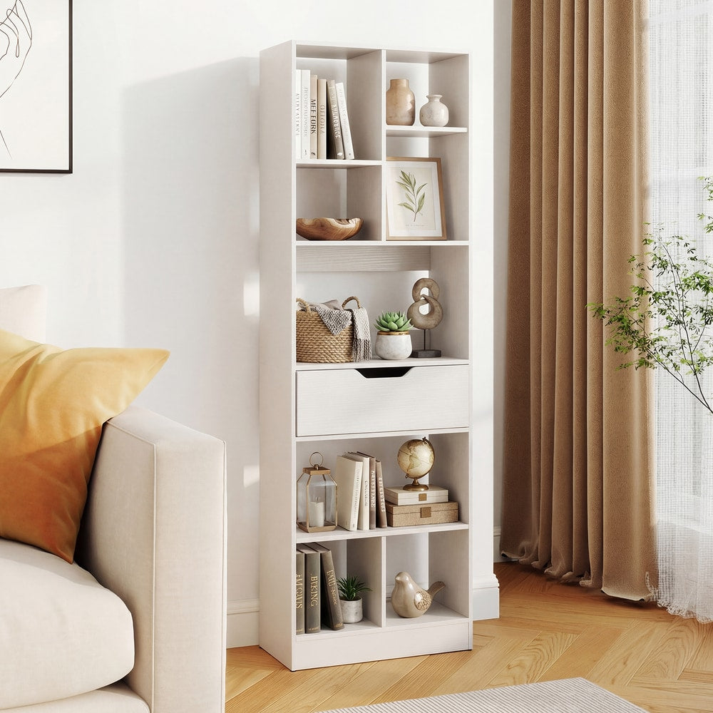 The white bookcase with a drawer and eight open cubes shown in a living room setting next to a sofa