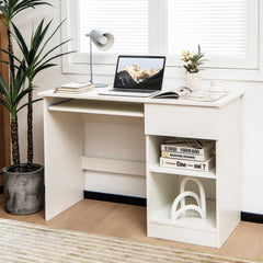 White computer desk with a laptop on the keyboard tray, set up in a room