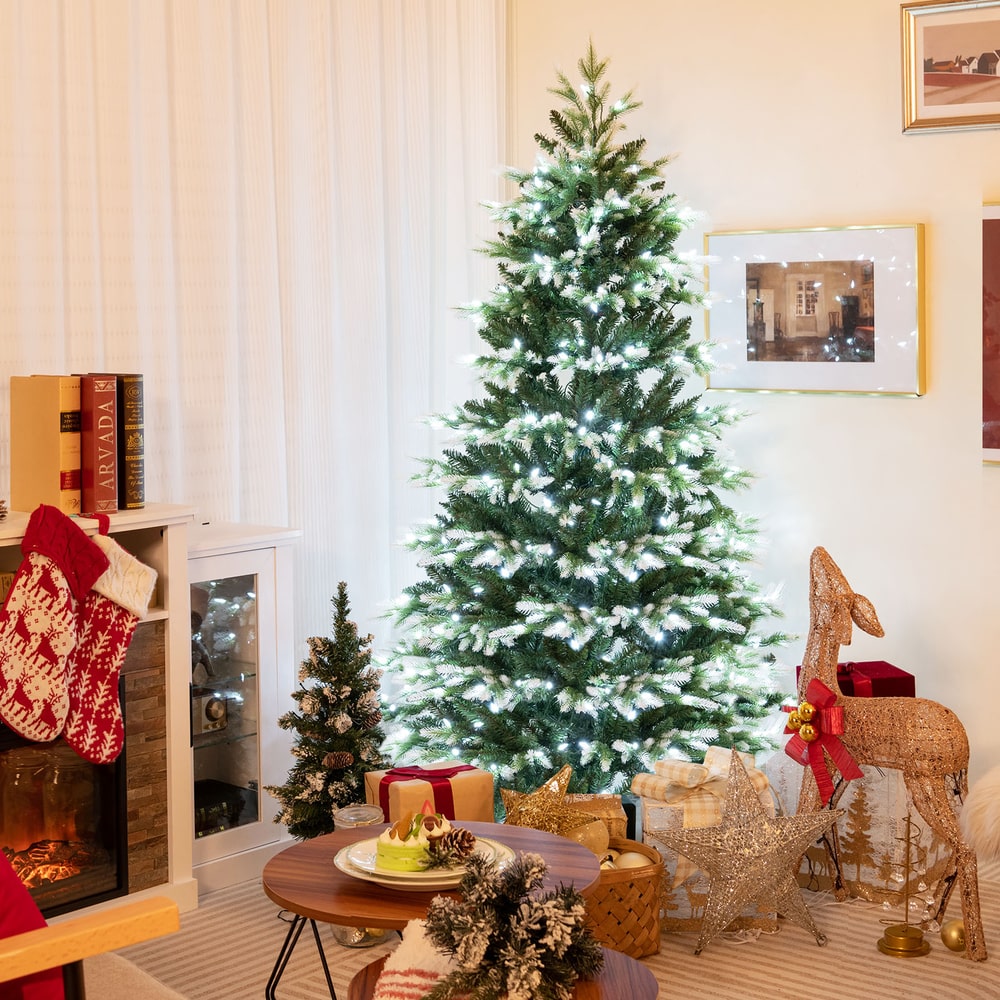 The Christmas tree is displayed in a living room setting with gifts and festive decorations