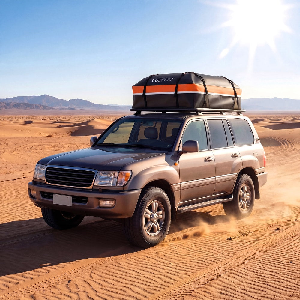 The orange and black roof bag is on a car driving on a sandy road