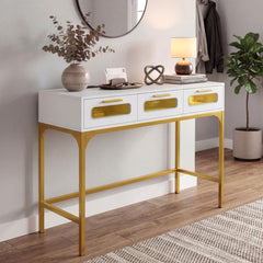White console table with gold legs in a hallway setting with a lamp and plant
