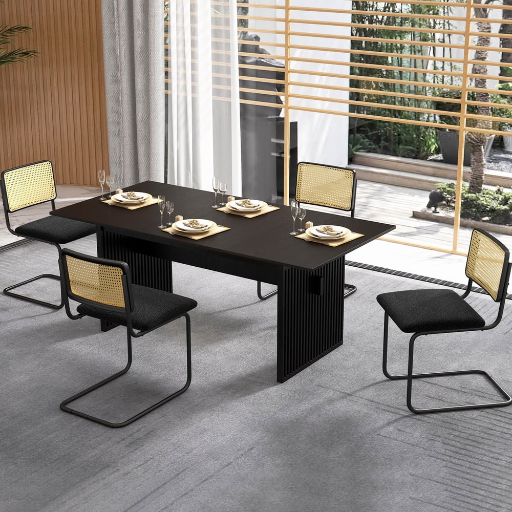 Four black cantilever dining chairs around a black dining table in a modern room
