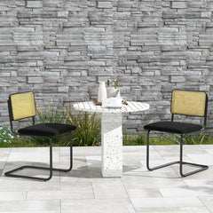 Two black cantilever dining chairs beside a terrazzo table on a patio