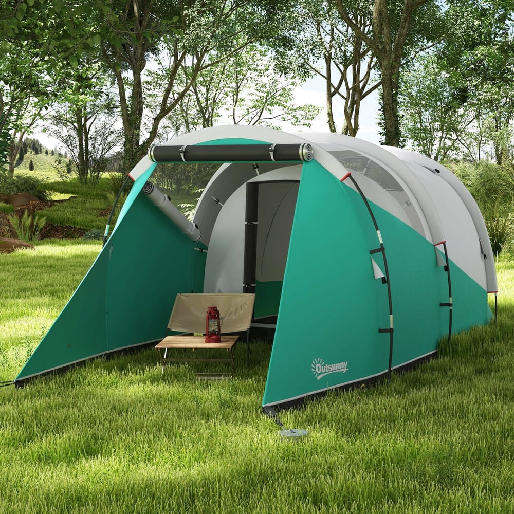 The tunnel tent set up in a grassy field with a small folding chair and lantern inside the entrance