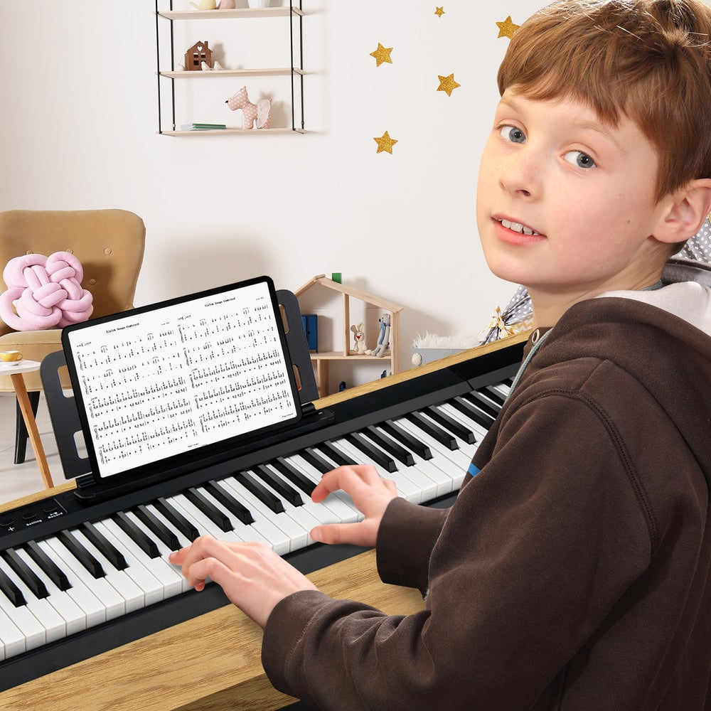 Young boy playing the electronic keyboard in a room, with sheet music on the stand