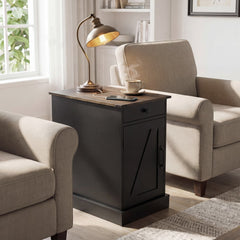 The black bedside table with a drawer and cupboard, next to a chair