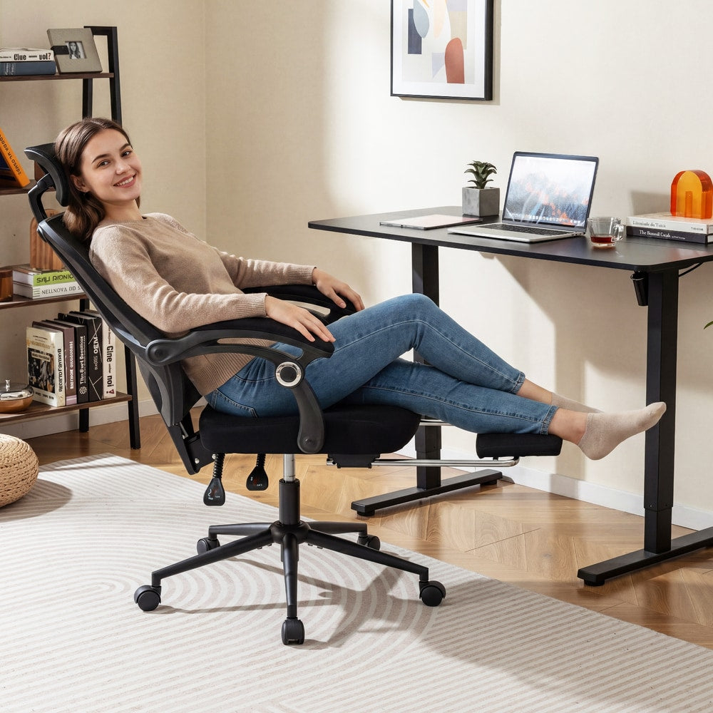 Woman relaxing in a black mesh office chair with her feet up on the footrest