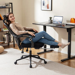 Woman relaxing in a black mesh office chair with her feet up on the footrest