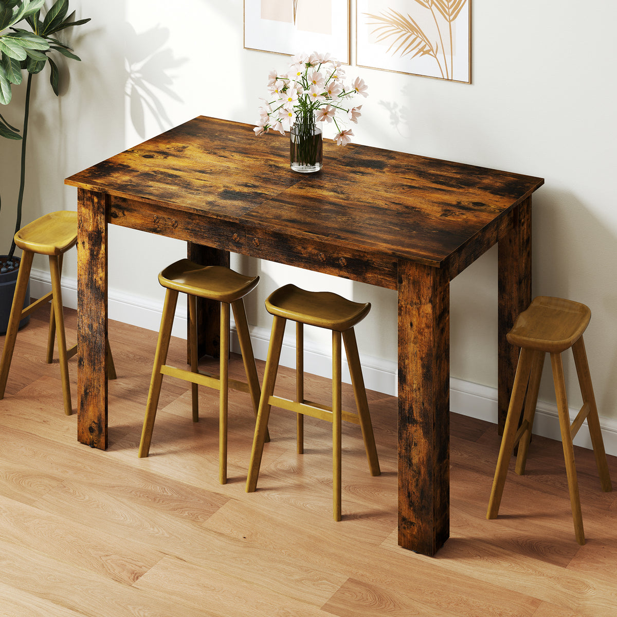 The dining table set with four wooden stools in a bright room with a vase of flowers on top