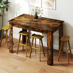 The dining table set with four wooden stools in a bright room with a vase of flowers on top