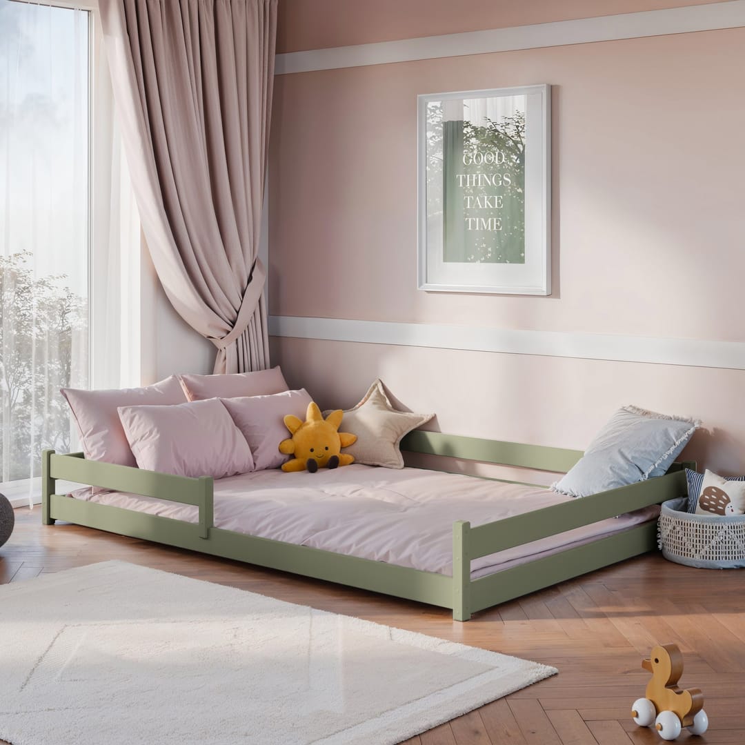 The sage green wooden bed frame in a child's bedroom with pink bedding and cushions