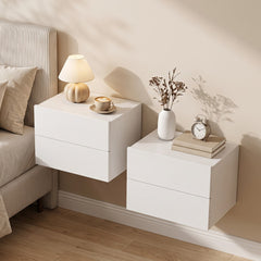 Two white bedside cabinets with drawers mounted on a wall next to a bed