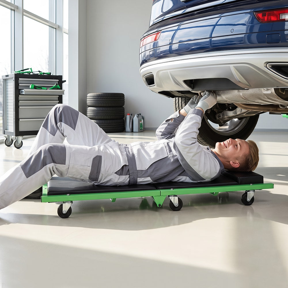 Mechanic lying on a green creeper under a car in a garage