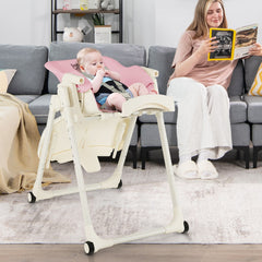 A baby sitting in the pink high chair while a woman reads a book