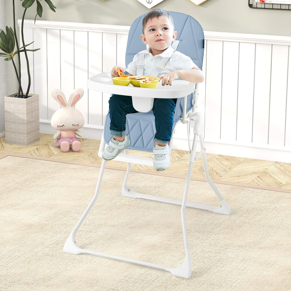 A baby sitting in the navy blue high chair at a table with toys and food