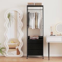 The black clothes rack styled in a bright bedroom beside a tall wavy mirror and vanity table