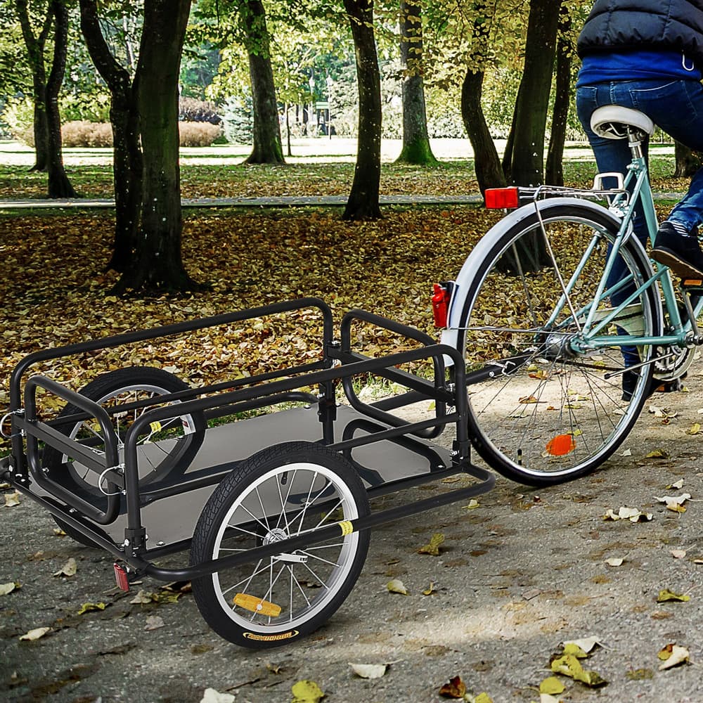 A person riding a bicycle with the black cargo trailer attached, being used for transport