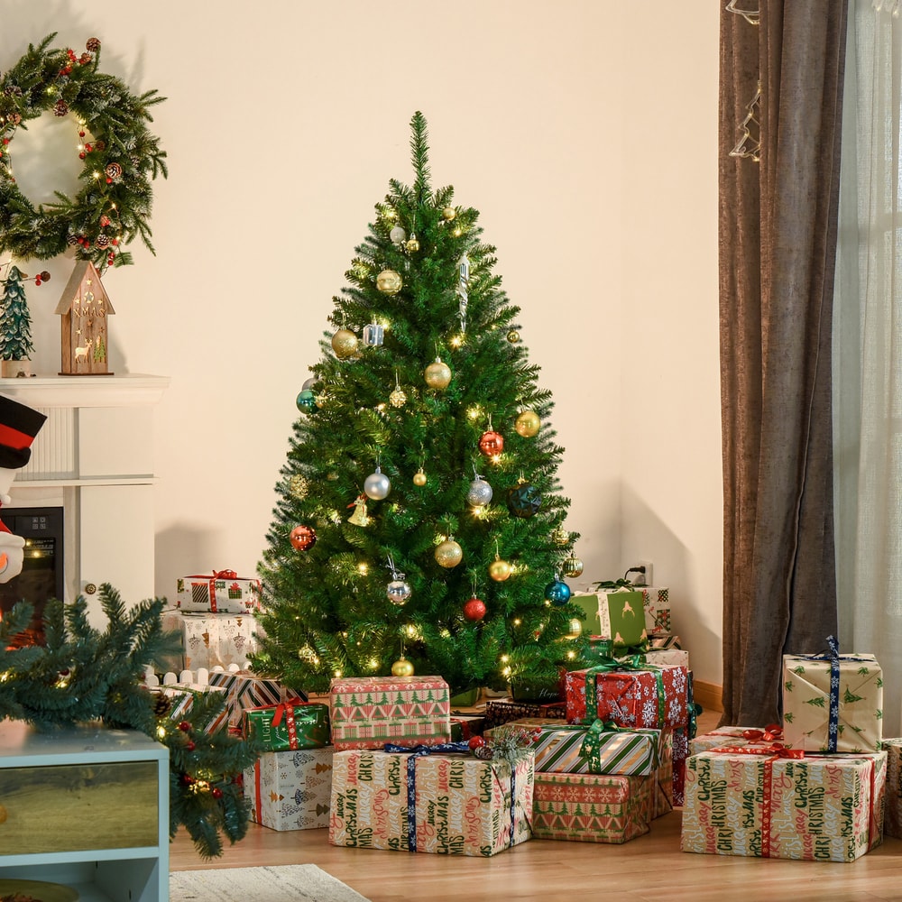 The artificial Christmas tree decorated with baubles and presents underneath in a cosy room setting