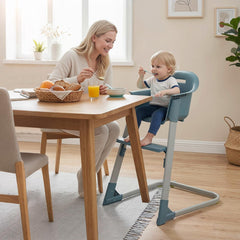 The high chair with a toddler sitting in it at a dining table during a meal