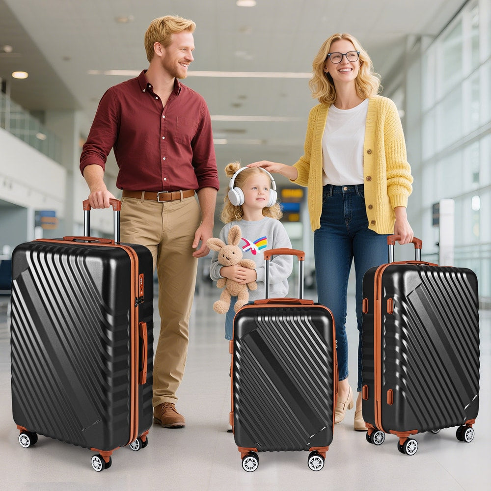 Three black suitcases with orange accents standing upright on a floor