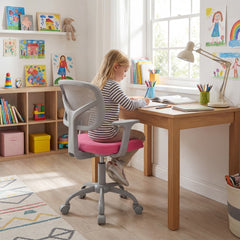 A young girl sits at a desk using the kids desk chair in a bright room
